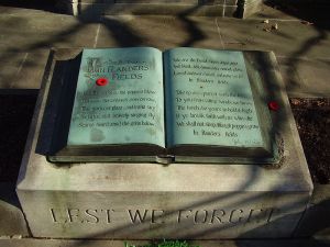 A memorial located outside John McCrae House in Guelph, Ontario. The memorial features John McCrae's "In Flanders Fields", with two Canadian-style remembrance poppies laid on top. 